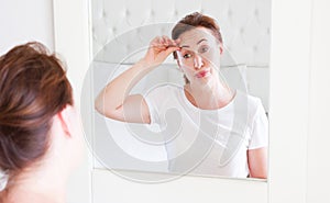 Middle age woman looking in mirror on face wrinkle forehead in bedroom. Wrinkles and anti aging skin care concept. Selective focus