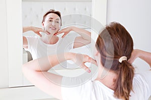 Middle age woman looking in mirror on face. Wrinkles and anti aging skin care concept. Selective focus