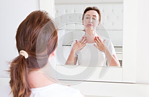 Middle age woman looking in mirror on wrinkle face on forehead. Menopause, Wrinkles and anti aging skin care concept. Selective