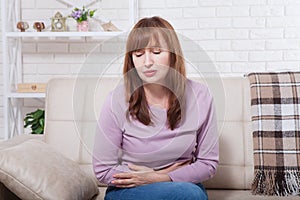 Middle age Woman with menstruation periods stomach pain at home background. Copy space and mock up. Menopause concept photo