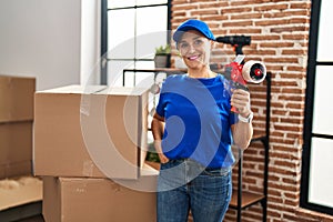 Middle age woman moving worker holding tape packing machine at new home