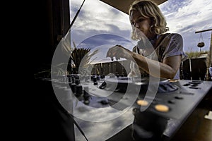 Middle age woman playing music as disk jokey in a beautiful location on the Caparica beach in Lisbon, Portugal. Playful woman