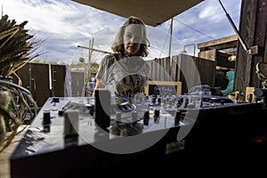 Middle age woman playing music as disk jokey in a beautiful location on the Caparica beach in Lisbon, Portugal. Playful woman