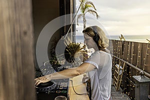 Middle age woman playing music as disk jokey in a beautiful location on the Caparica beach in Lisbon, Portugal. Playful woman