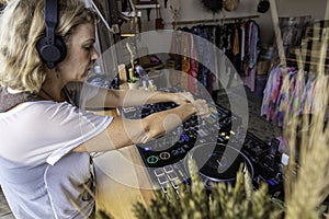 Middle age woman playing music as disk jokey in a beautiful location on the Caparica beach in Lisbon, Portugal. Playful woman