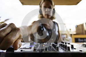 Middle age woman playing music as disk jokey in a beautiful location on the Caparica beach in Lisbon, Portugal. Playful woman