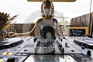 Middle age woman playing music as disk jokey in a beautiful location on the Caparica beach in Lisbon, Portugal. Playful woman