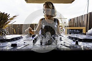 Middle age woman playing music as disk jokey in a beautiful location on the Caparica beach in Lisbon, Portugal. Playful woman