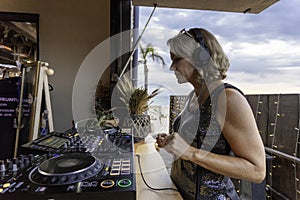 Middle age woman playing music as disk jokey in a beautiful location on the Caparica beach in Lisbon, Portugal. Playful woman