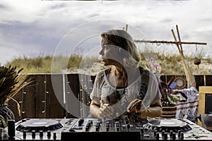 Middle age woman playing music as disk jokey in a beautiful location on the Caparica beach in Lisbon, Portugal. Playful woman photo