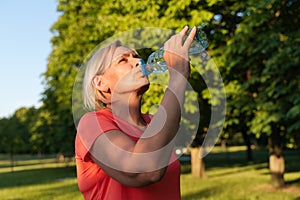 Middle age woman portrait with plastic water bottle doing sports outdoors
