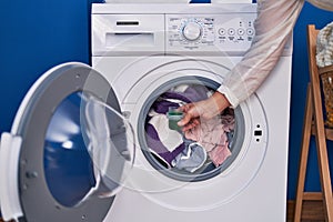 Middle age woman pouring detergent on washing machine at laundry room