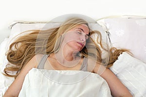 Middle age woman real portrait bed bedroom blonde long hair fifty plus copy space 50 blanket pillow face sleep fever sick