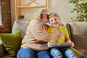 Middle age woman and school age boy, granny and grandson sitting at home and talking, having fun. Concept of emotions