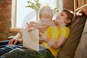 Middle age woman and school age boy, granny and grandson sitting at home and talking, having fun. Concept of emotions