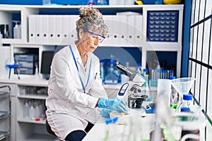 Middle age woman scientist mixing on bowl at laboratory photo