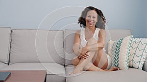 Middle age woman smiling confident sitting on sofa at home