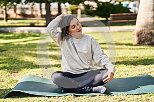 Middle age woman smiling confident stretching head at park