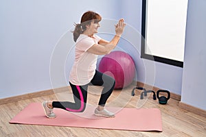 Middle age woman smiling confident training legs exercise at sport center