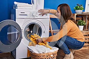 Middle age woman smiling confident washing clothes at laundry room