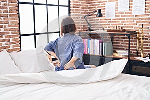 Middle age woman suffering for back injury sitting on bed at bedroom