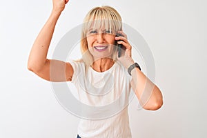 Middle age woman talking on the smartphone standing over isolated white background annoyed and frustrated shouting with anger,