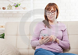 Middle age woman using smartphone at home background. Copy space and mock up. Online shopping, internet technology on cellphone.