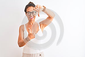 Middle age woman wearing casual t-shirt and glasses standing over isolated white background smiling making frame with hands and