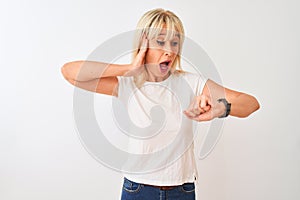 Middle age woman wearing casual t-shirt standing over isolated white background Looking at the watch time worried, afraid of