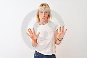 Middle age woman wearing casual t-shirt standing over isolated white background Moving away hands palms showing refusal and denial