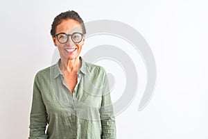 Middle age woman wearing green shirt and glasses standing over isolated white background with a happy and cool smile on face