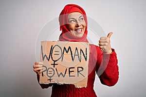 Middle age woman wearing muslim hijab asking for women rights holding banner pointing and showing with thumb up to the side with