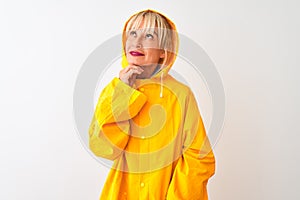 Middle age woman wearing rain coat with hood standing over isolated white background with hand on chin thinking about question,