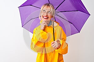 Middle age woman wearing rain coat and purple umbrella over isolated white background serious face thinking about question, very