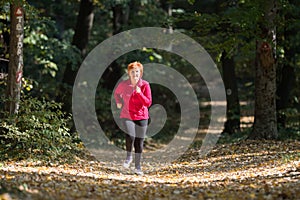 Middle age woman wearing sportswear and running in forest