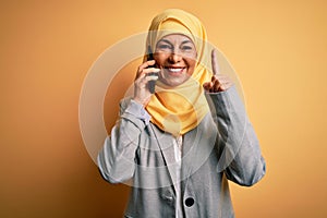 Middle age woman wearing traditional muslim hijab having conversation talking on smartphone surprised with an idea or question