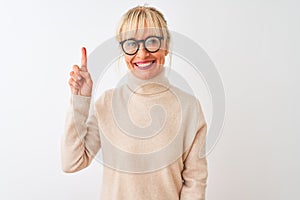 Middle age woman wearing turtleneck sweater and glasses over isolated white background showing and pointing up with finger number