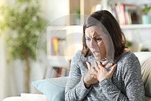 Middle age woman wheezing touching chest at home