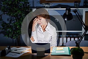 Middle age woman working at the office at night tired rubbing nose and eyes feeling fatigue and headache