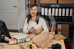 Middle age woman working at small bracelets business ecommerce looking at the camera blowing a kiss being lovely and sexy