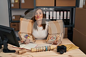 Middle age woman working at small bracelets business ecommerce looking at the camera blowing a kiss being lovely and sexy