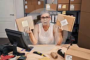 Middle age woman working at small business ecommerce clueless and confused expression