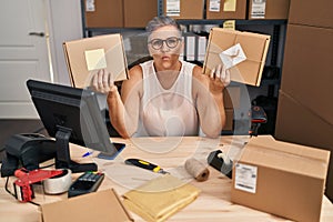 Middle age woman working at small business ecommerce looking at the camera blowing a kiss being lovely and sexy