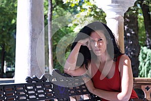 Middle-aged adult Hispanic woman with black curly hair, sitting on a park bench, angry. Concept anger, argument, problems, couple