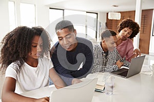 Middle aged African American  parents helping their teenage kids using laptops to do homework, close up