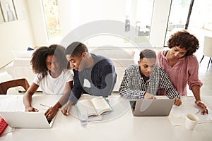 Middle aged African American  parents helping their teenage kids using laptops to do homework, elevated view