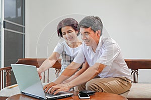 Middle aged asian couple using laptop at home
