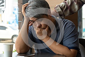 Middle-aged Asian man 40 years old, stressed and tired, are sitting in fast food restaurant and have friends standing behind to en