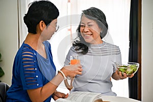 A middle-aged Asian woman enjoys talking with her friends while having a healthy breakfast together