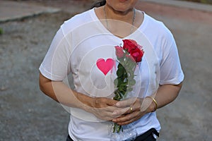 Middle aged asian woman is holding a beautiful bouquet of red roses. Love and romance Valentine`s day concept.